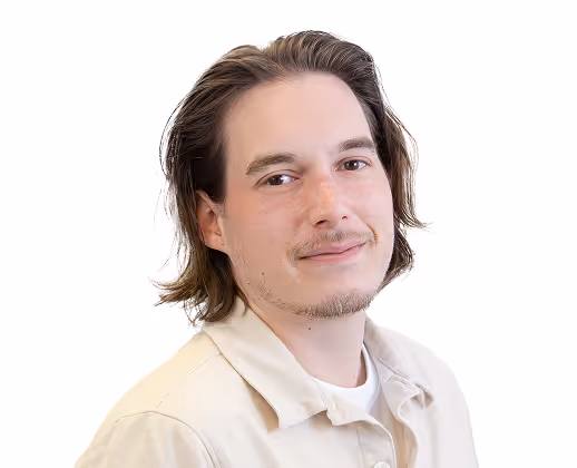 Jeune homme souriant avec cheveux mi-longs portant une veste claire et un t-shirt blanc.