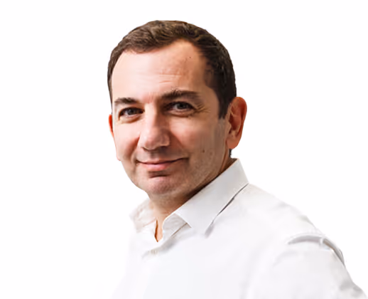 Homme souriant portant une chemise blanche sur fond blanc.