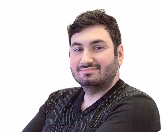 Homme aux cheveux courts et barbe portant un pull noir, souriant légèrement devant un fond blanc.