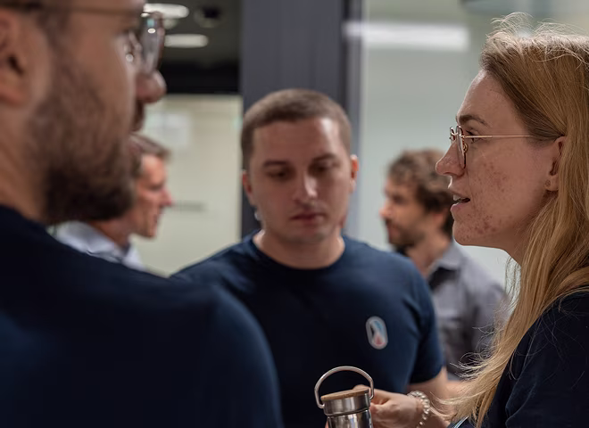 Deux femmes et deux hommes debout en conversation dans un environnement de bureau moderne.