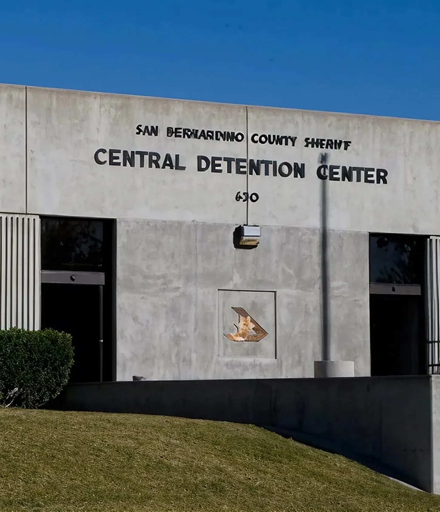 San Bernardino County Sheriff Central Detention Center building with clear blue sky and a grassy area in front.