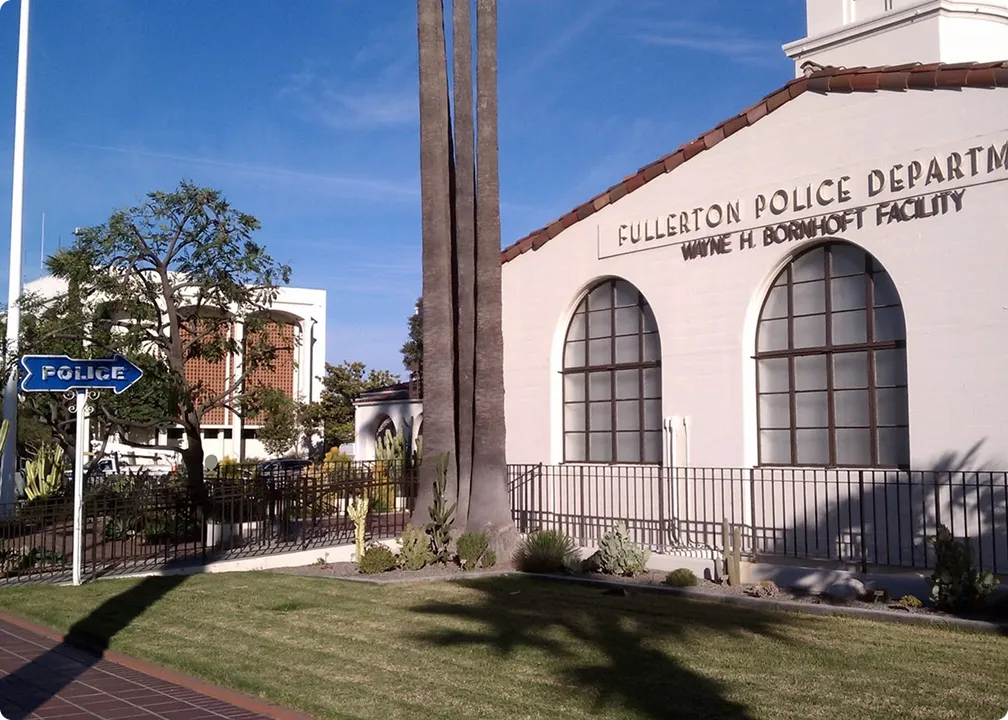 Fullerton Police Department Wayne H. Bornhoft Facility building under clear blue sky with palm trees and a blue police sign on a white post.