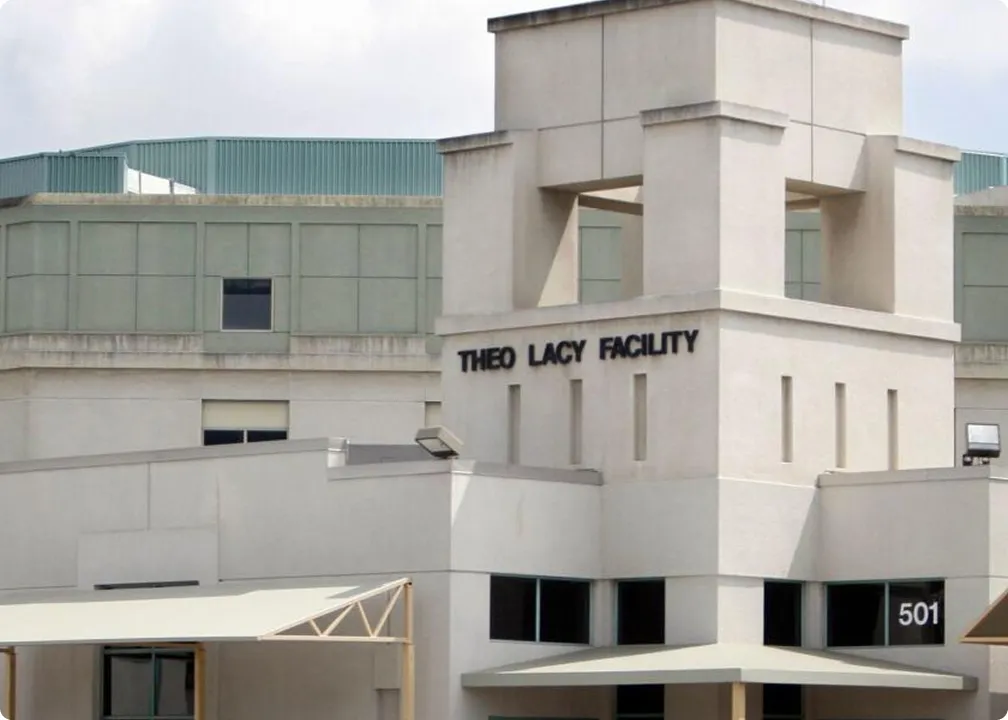 Exterior view of the Theo Lacy Facility building with beige walls, large windows, and the number 501 visible.