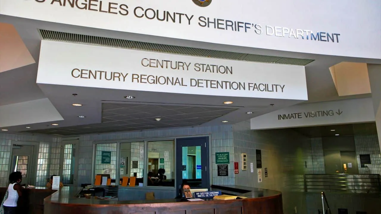 Reception desk inside the Century Regional Detention Facility with signage for Los Angeles County Sheriff's Department and inmate visiting.