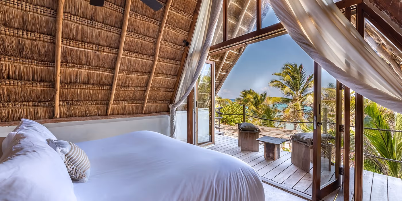 Luxury thatched-roof suite at La Valise San Miguel Hotel opening onto a private balcony with breathtaking views of the tropical jungle and sea.