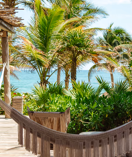 Beachfront terrace with a hammock and palm trees at La Valise San Miguel Hotel restaurant.