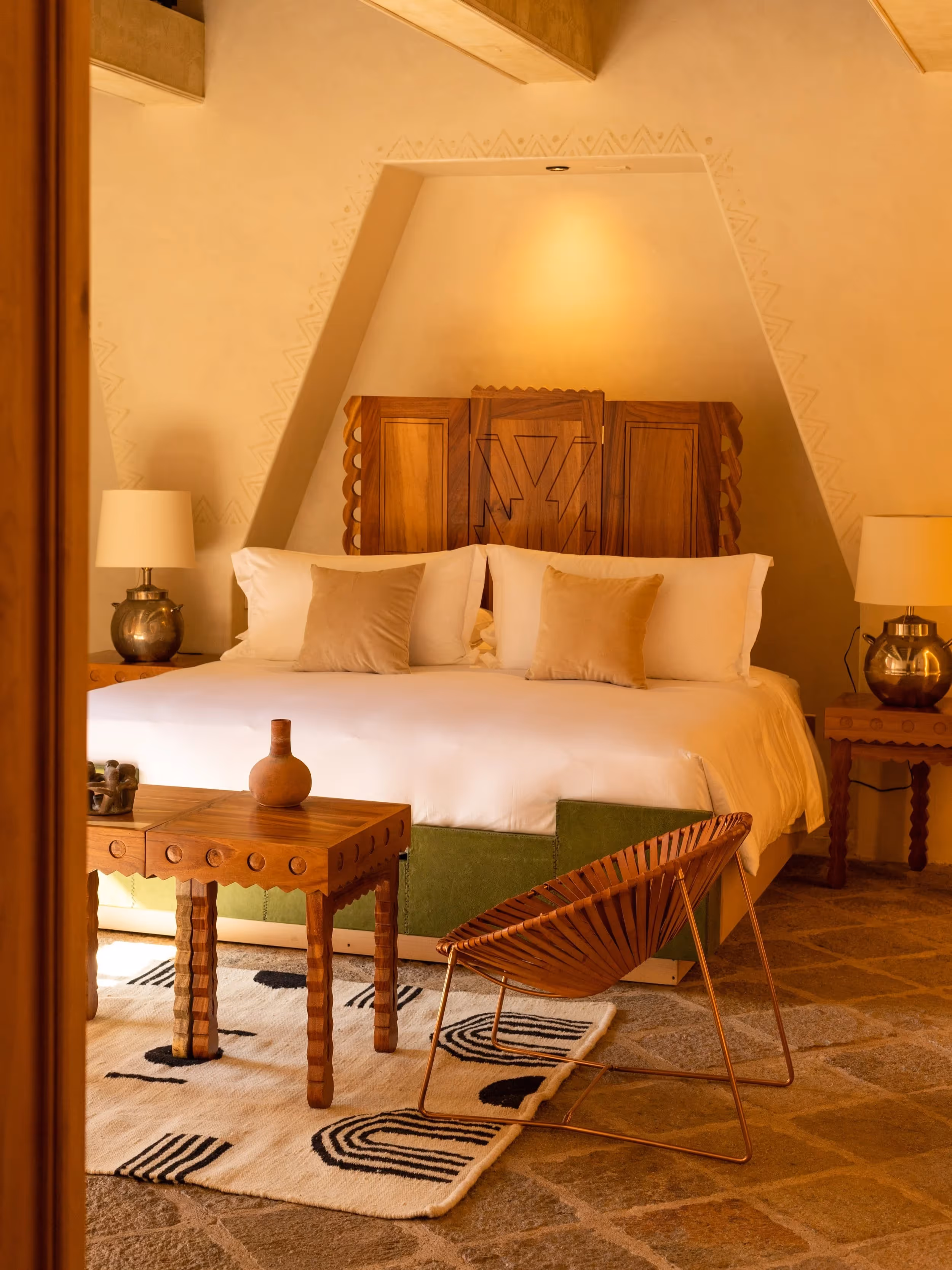 Lujosa suite para huéspedes con cama king size, cabecera de madera hecha a mano y cálidos muebles de diseño en La Valise San Miguel Hotel.