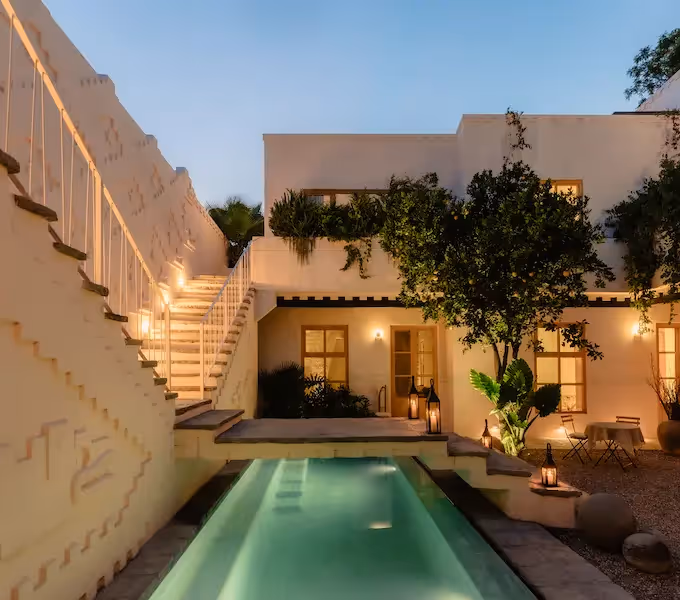 El lujoso patio del hotel La Valise San Miguel cuenta con una piscina iluminada, escaleras de piedra y arquitectura colonial al anochecer.