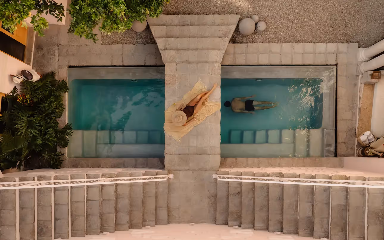 Aerial view of the designer pool at La Valise San Miguel Hotel featuring a couple relaxing in a luxurious, minimalist setting.