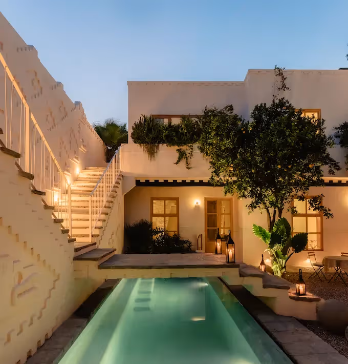 Luxury pool illuminated at night with a designer staircase and Mediterranean architecture at La Valise San Miguel Hotel.