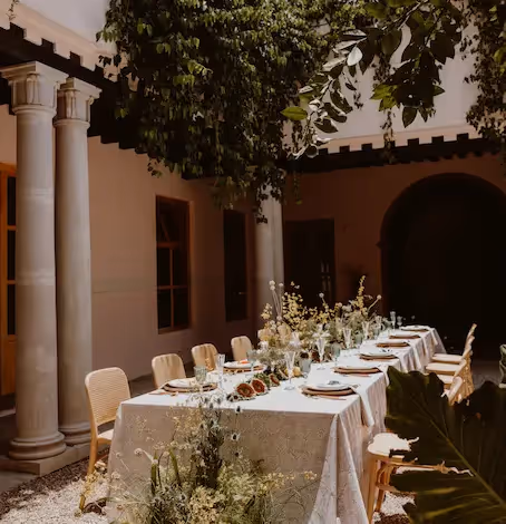 Elegante mesa de comedor larga situada bajo una exuberante vegetación en el restaurante con patio al aire libre del hotel La Valise San Miguel.