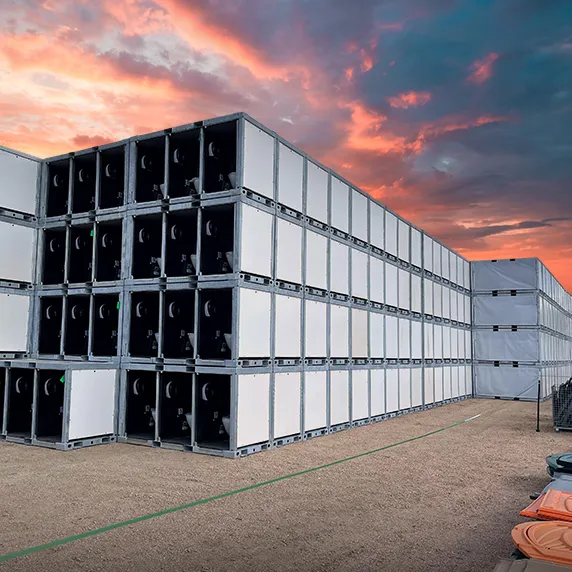 Stacked portable restroom units with white panels outdoors at sunset