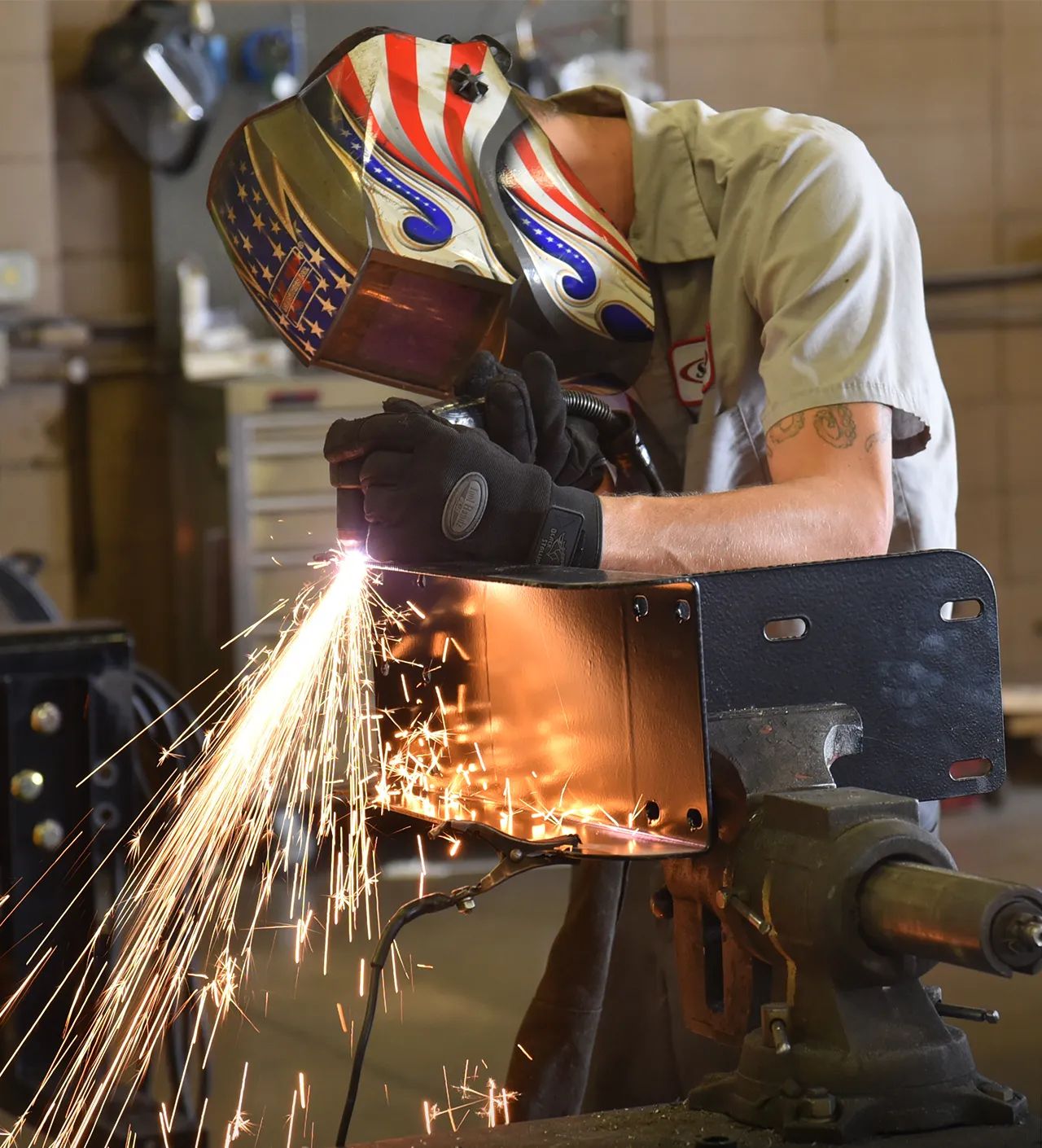 Person welding metal part with sparks flying in workshop