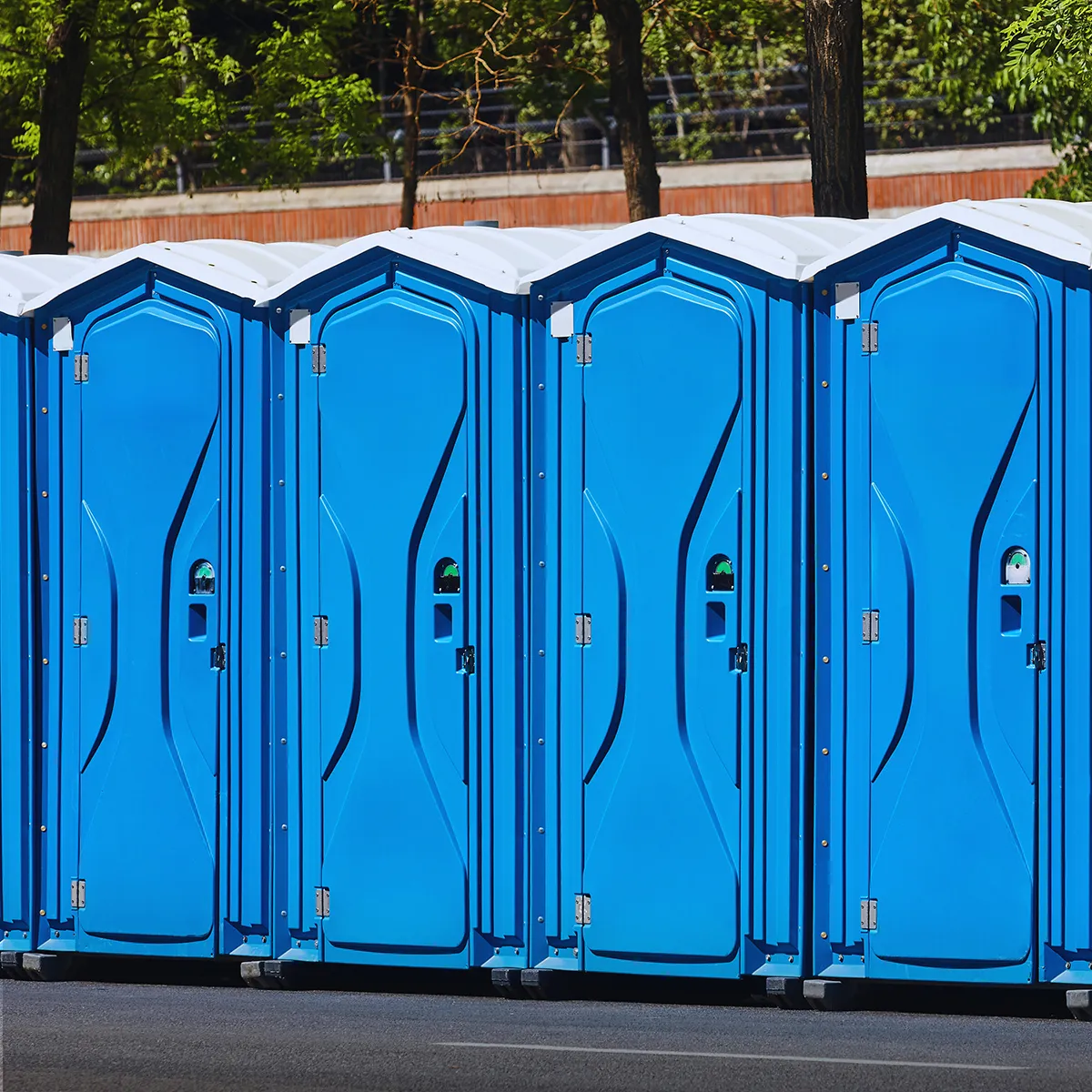 Row of blue portable restrooms with white roofs outdoors