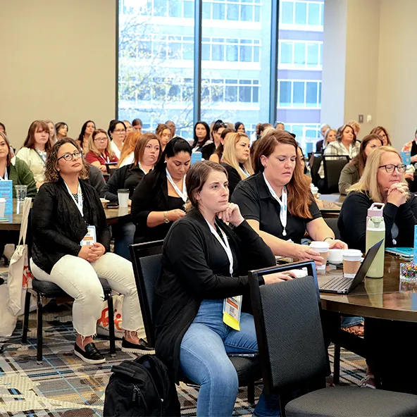 Group of people seated indoors at conference or seminar listening attentively