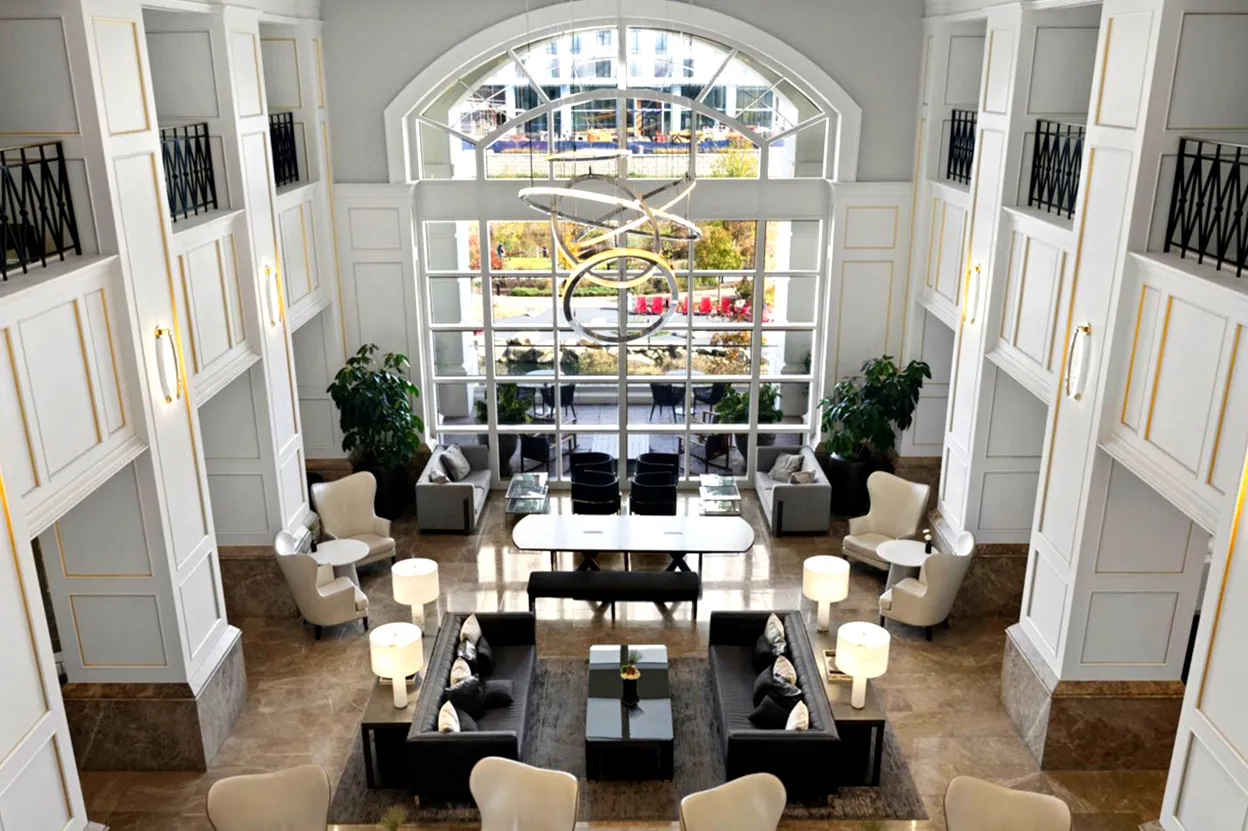 Hotel lobby seating area with large arched window and modern chandelier