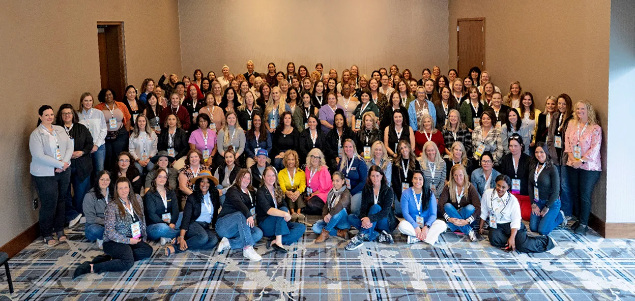 Large group of women posing together at an indoor conference or event