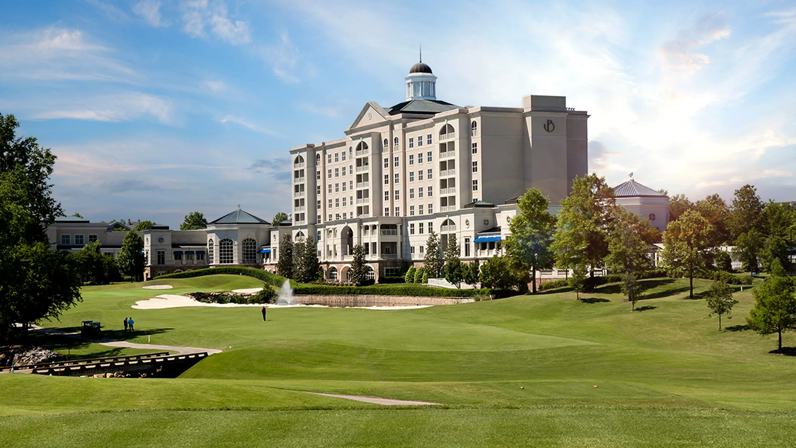 Large hotel building with cupola near golf course and landscaped grounds