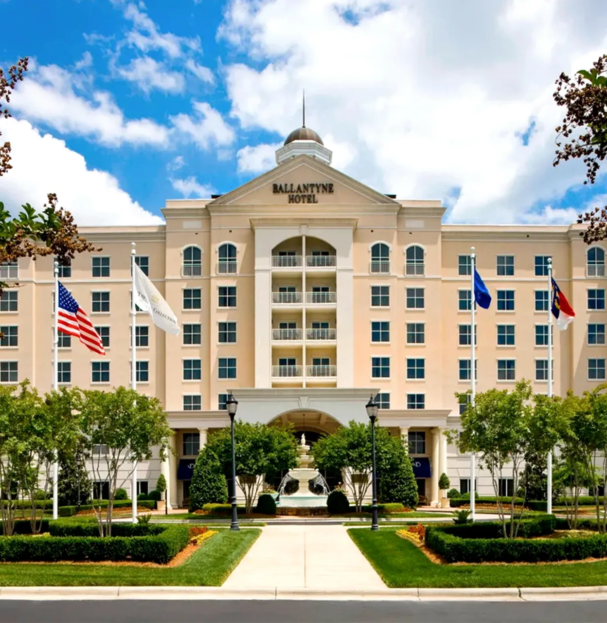 Ballantyne Hotel beige multi-story facade with flags and fountain in front