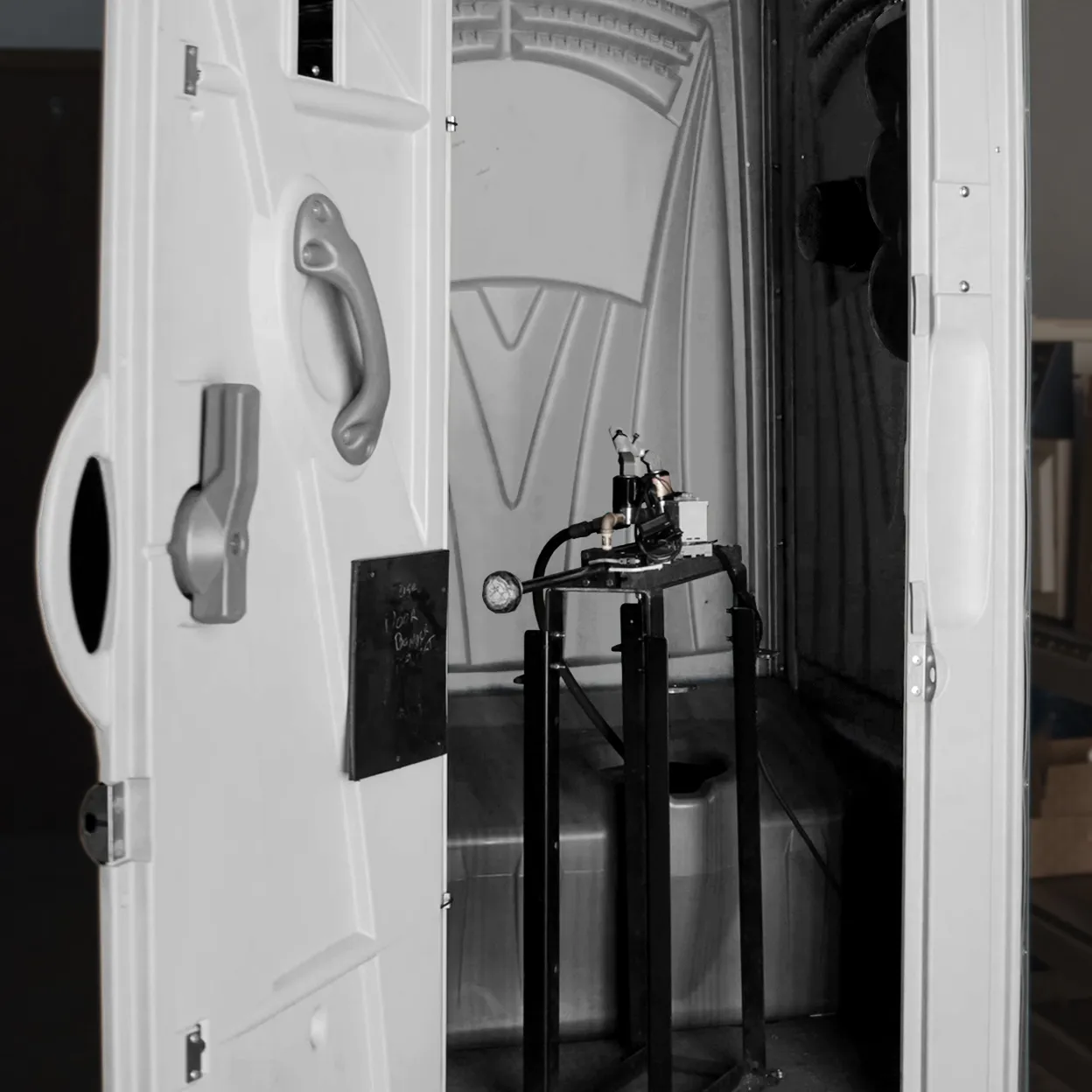 Interior of portable restroom with testing equipment mounted on a black metal stand
