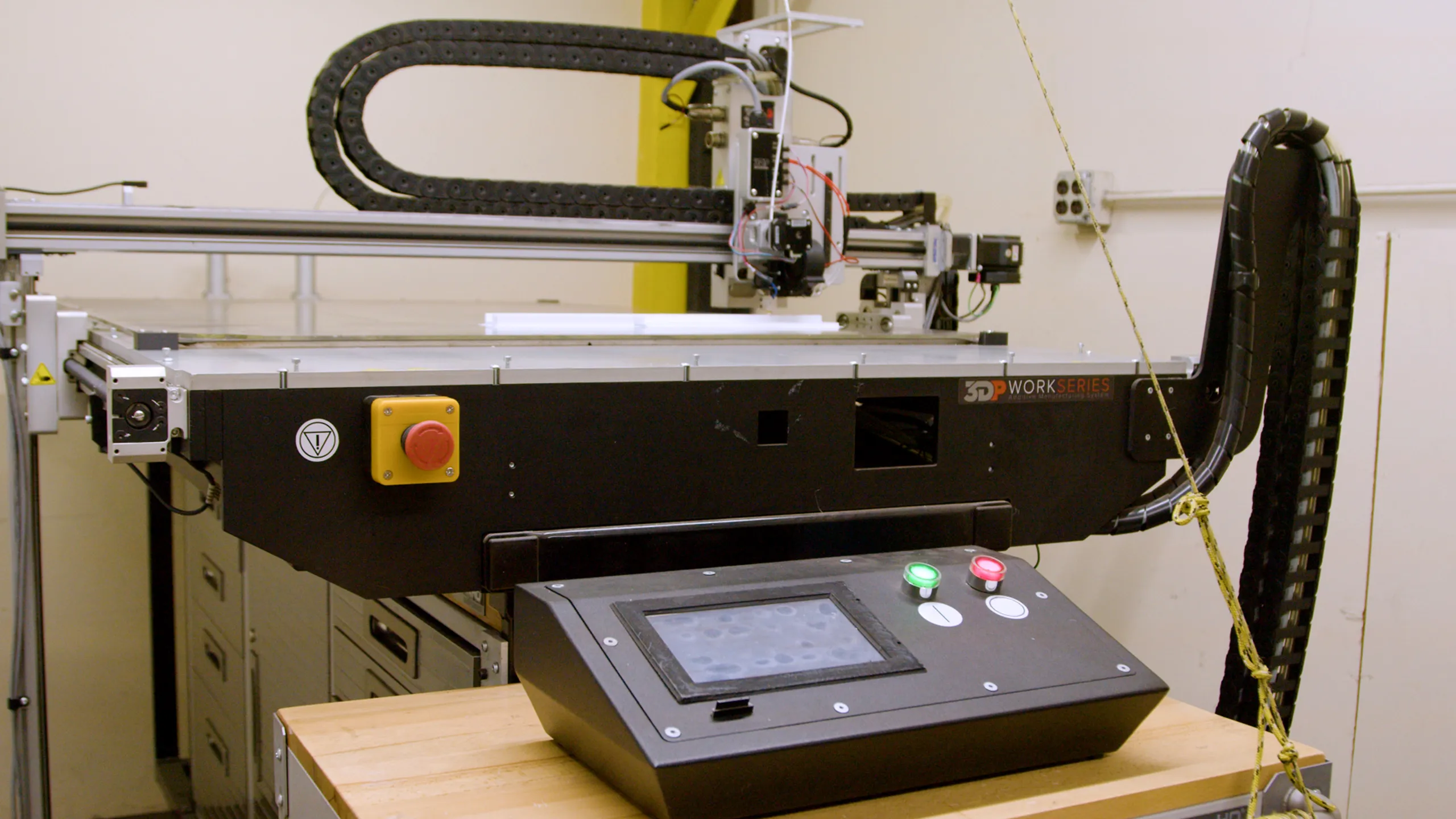 3D printer machine with control panel on wooden table in industrial room
