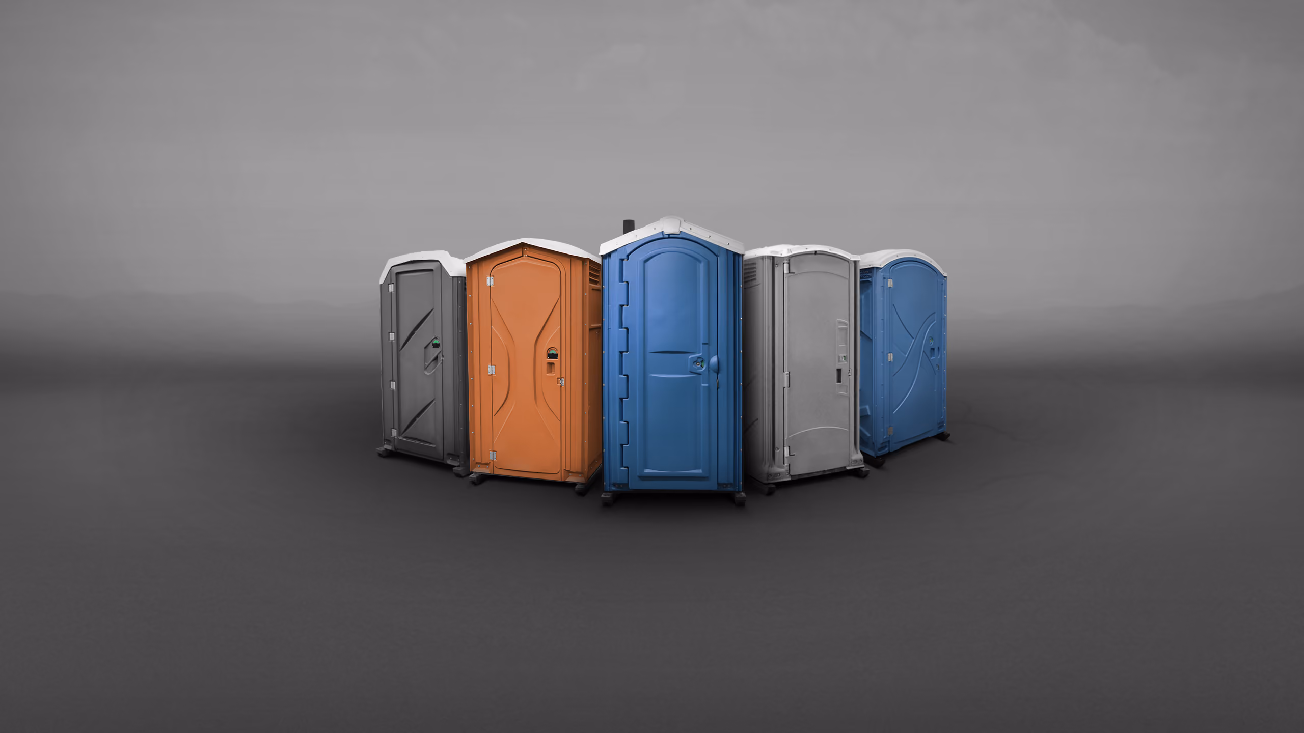 A group of portable toilets in various colors—orange, blue, gray—arranged in a semi-circle.