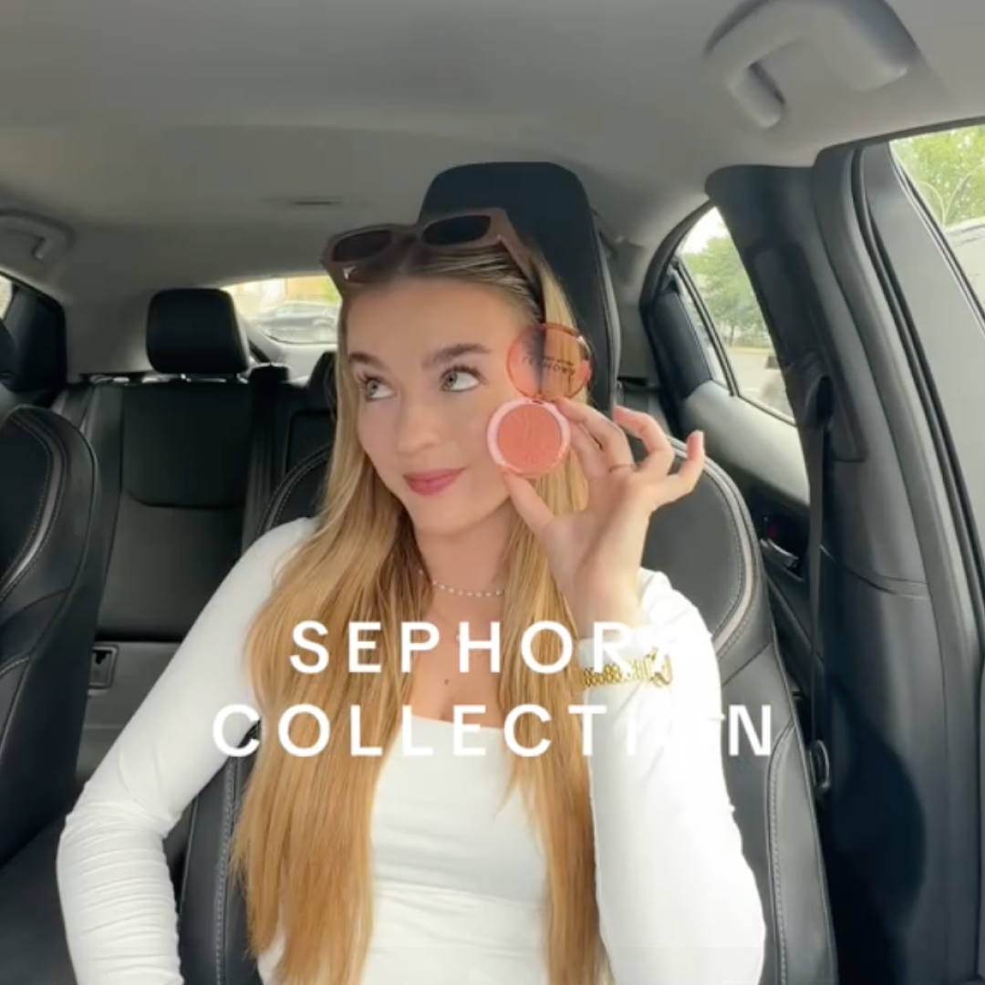 Young woman with long blonde hair sitting in a car holding up a Sephora blush compact near her face, with the text 'SEPHORA COLLECTION' overlaid.
