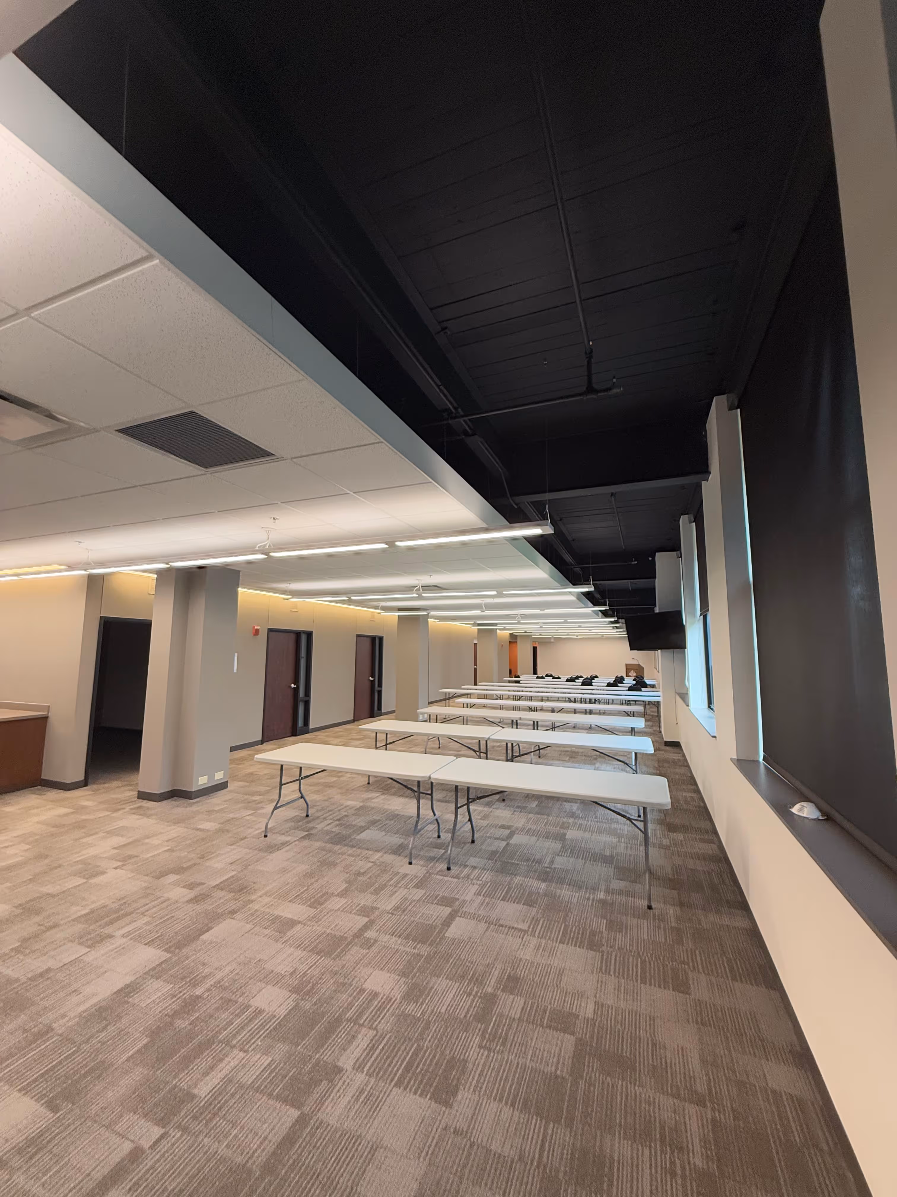 One of the Conference Spaces at The East End with multiple long folding tables arranged in rows and a mix of black and white ceiling panels.