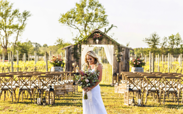 Bride holding bouquet in front of ceremony setup at vineyard