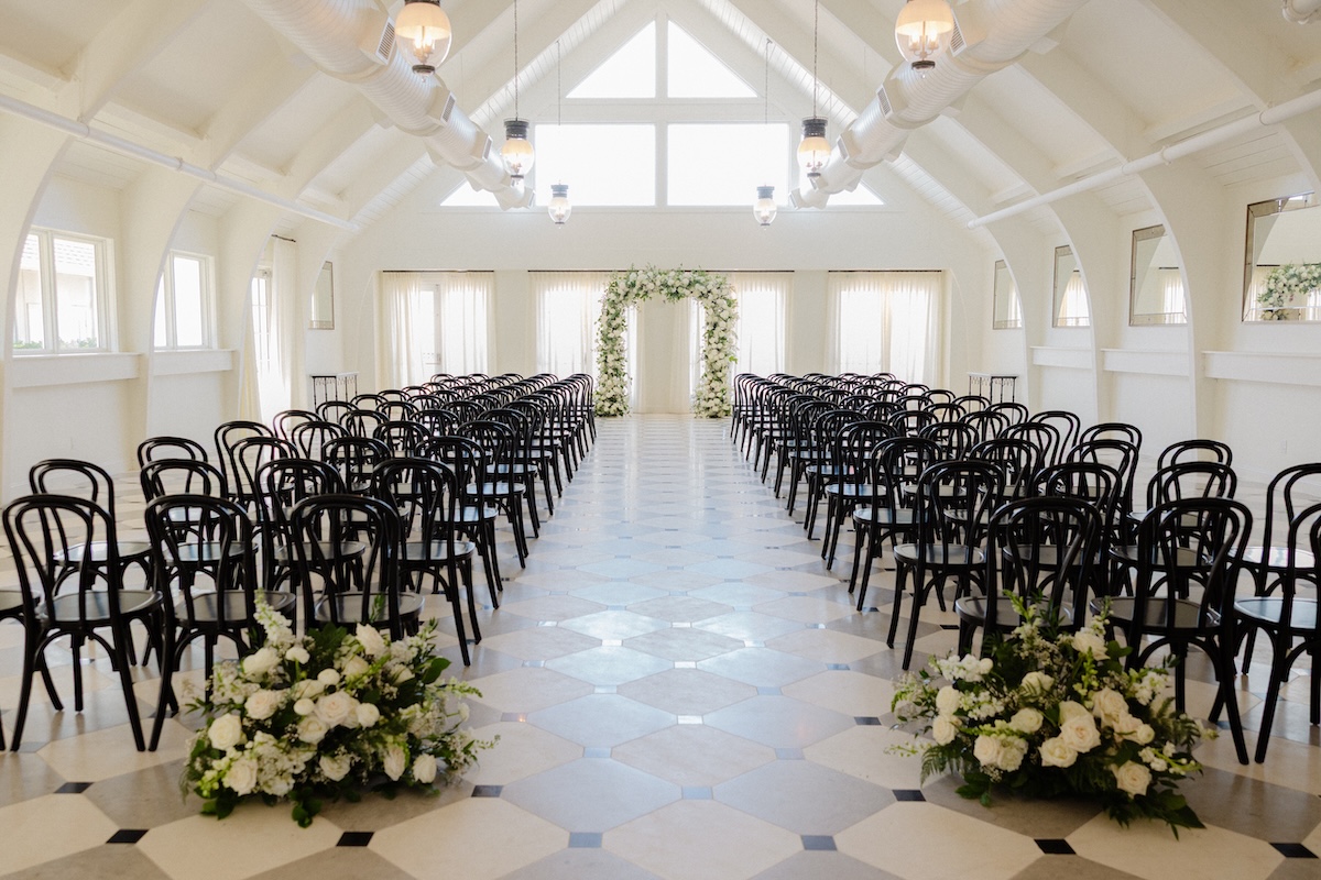 Outdoor wedding ceremony seating with black chairs arranged on a garden lawn surrounded by lush greenery in the Outer Banks.