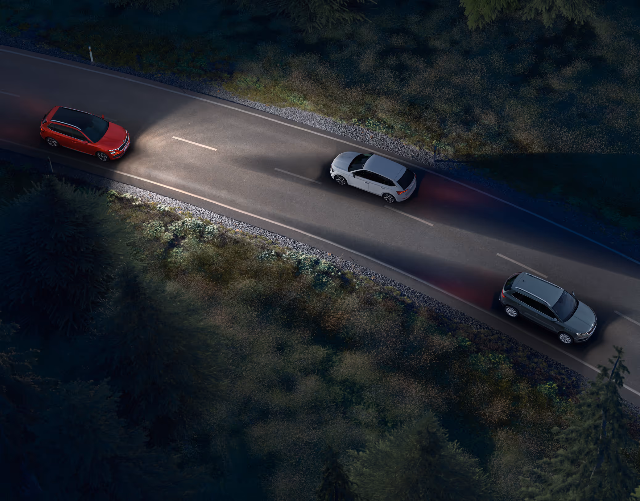 Animation des Dynamischen Fernlichtassistenten: Ein roter Škoda Kamiq Balance fährt nachts auf einer Landstraße und leuchtet die Fahrbahn mit Fernlicht aus. Das System erkennt entgegenkommende und vorausfahrende Fahrzeuge und blendet diese gezielt aus dem Lichtkegel aus, um eine Blendung zu vermeiden.