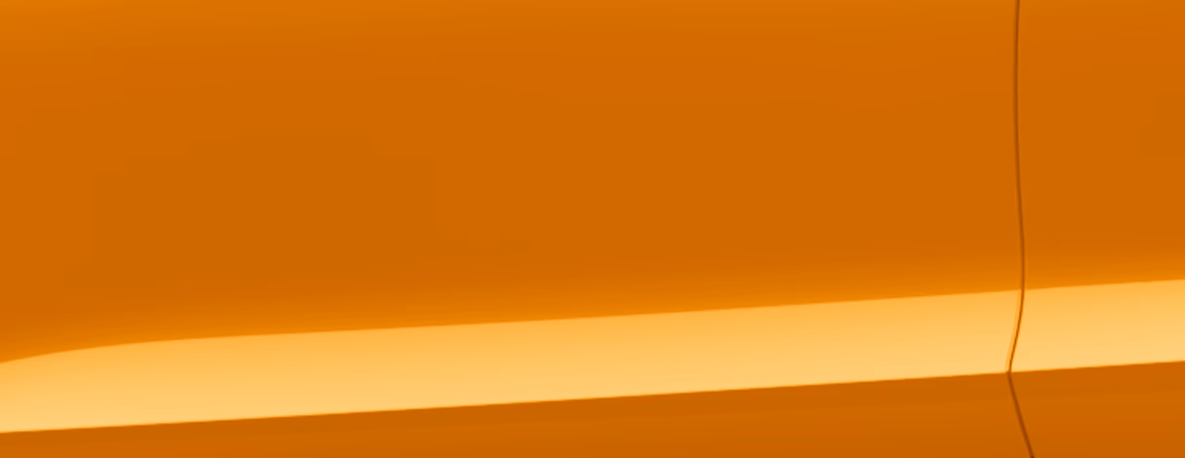 Eine minimalistische Detailaufnahme zeigt einen Ausschnitt der Karosserie des Škoda Kamiq Balance in der Lackierung Phoenix-Orange Metallic. 
