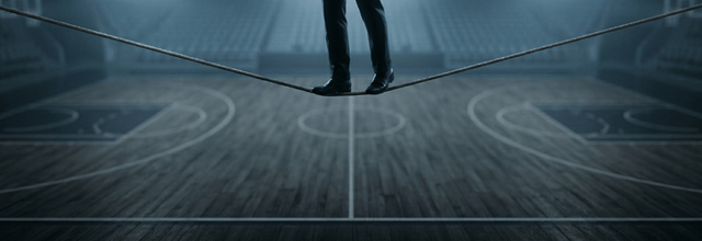 A tightrope walker above NBA basketball court illustrating razor thin moneyline margins