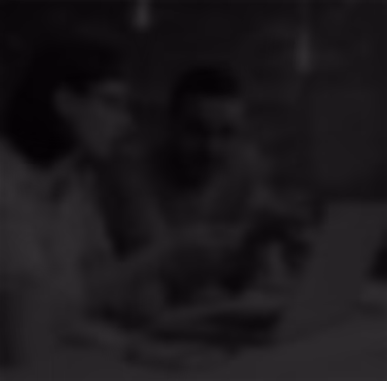 Two people sitting at a table with a laptop, engaged in a discussion.