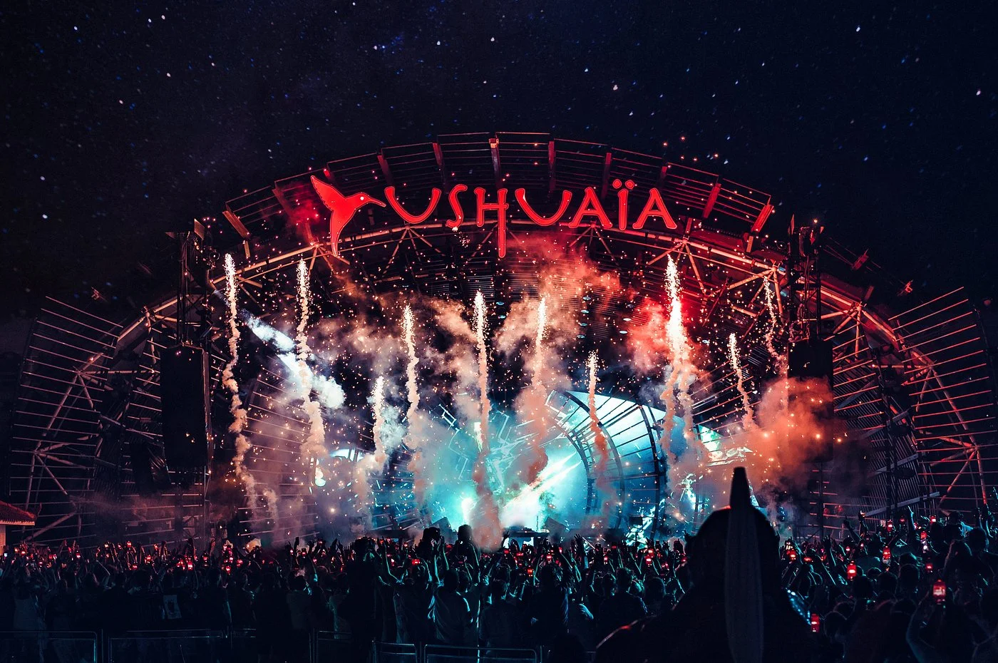 Crowd at a nighttime concert with fireworks and smoke effects on stage at Ushuaïa Ibiza.