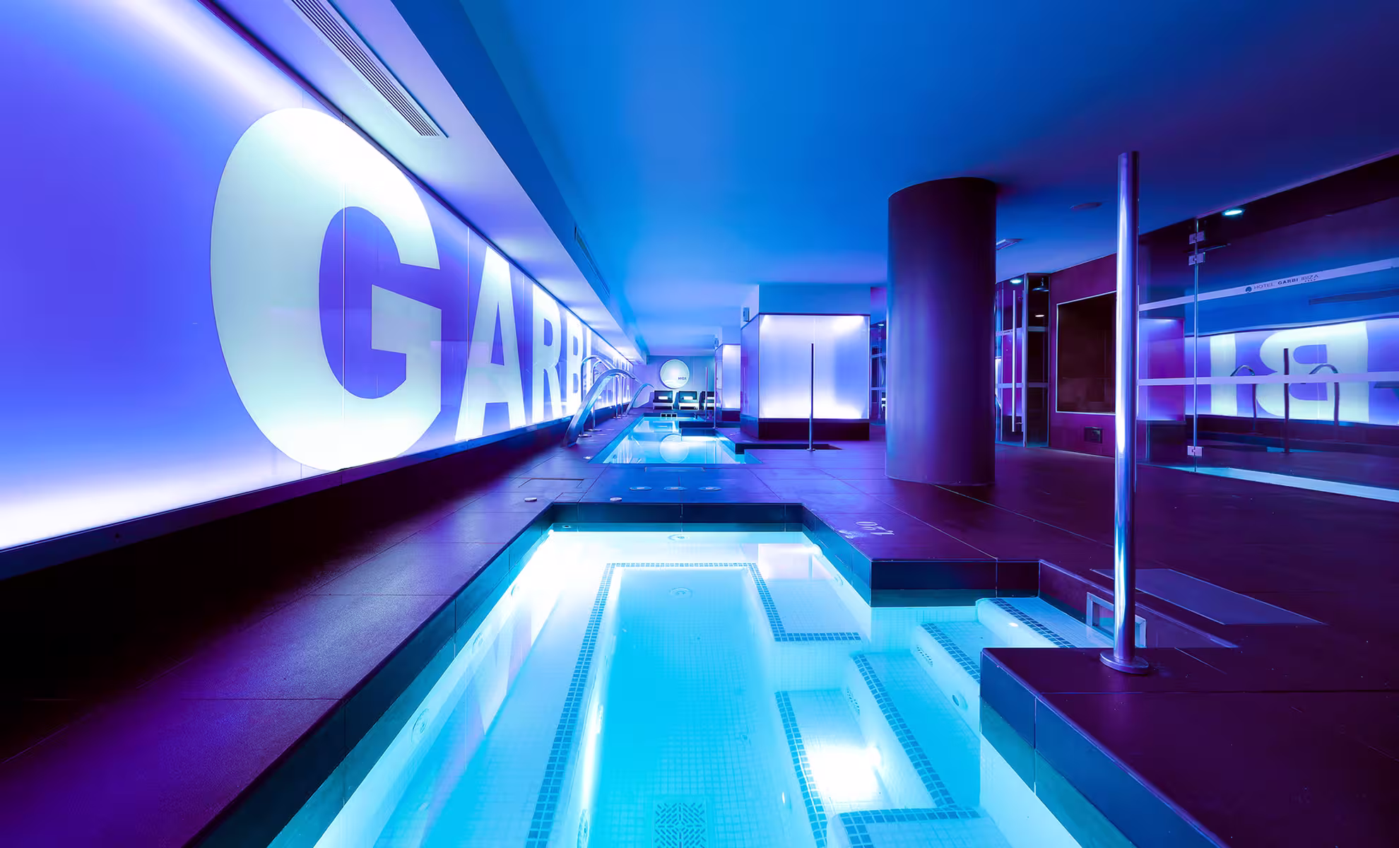 Indoor modern pool with purple ambient lighting and a sleek metal water spout.
