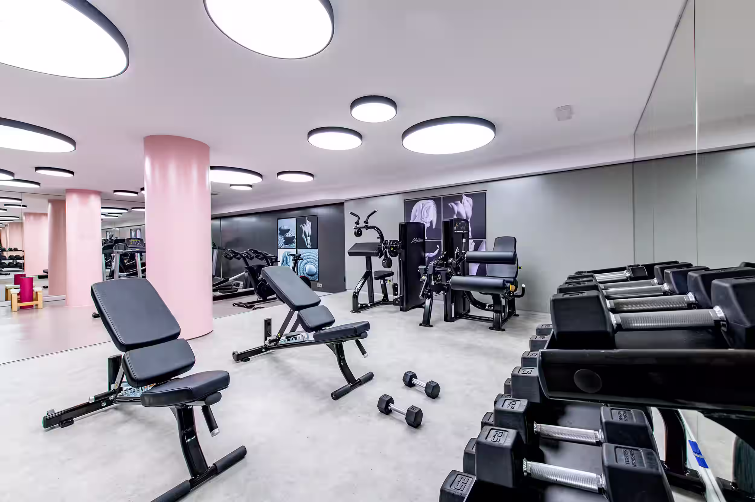 Modern gym with weight machine, exercise bike, treadmill, and wall fitness art.