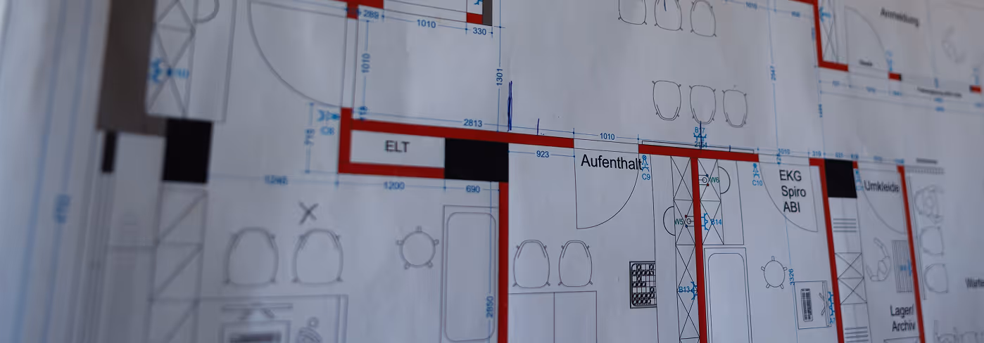 Nahaufnahme eines architektonischen Bauplans mit markierten Räumen und technischer Beschriftung.