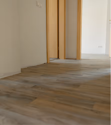 Blick auf einen Flur mit Holzfußboden und offener Tür zu drei Zimmern.