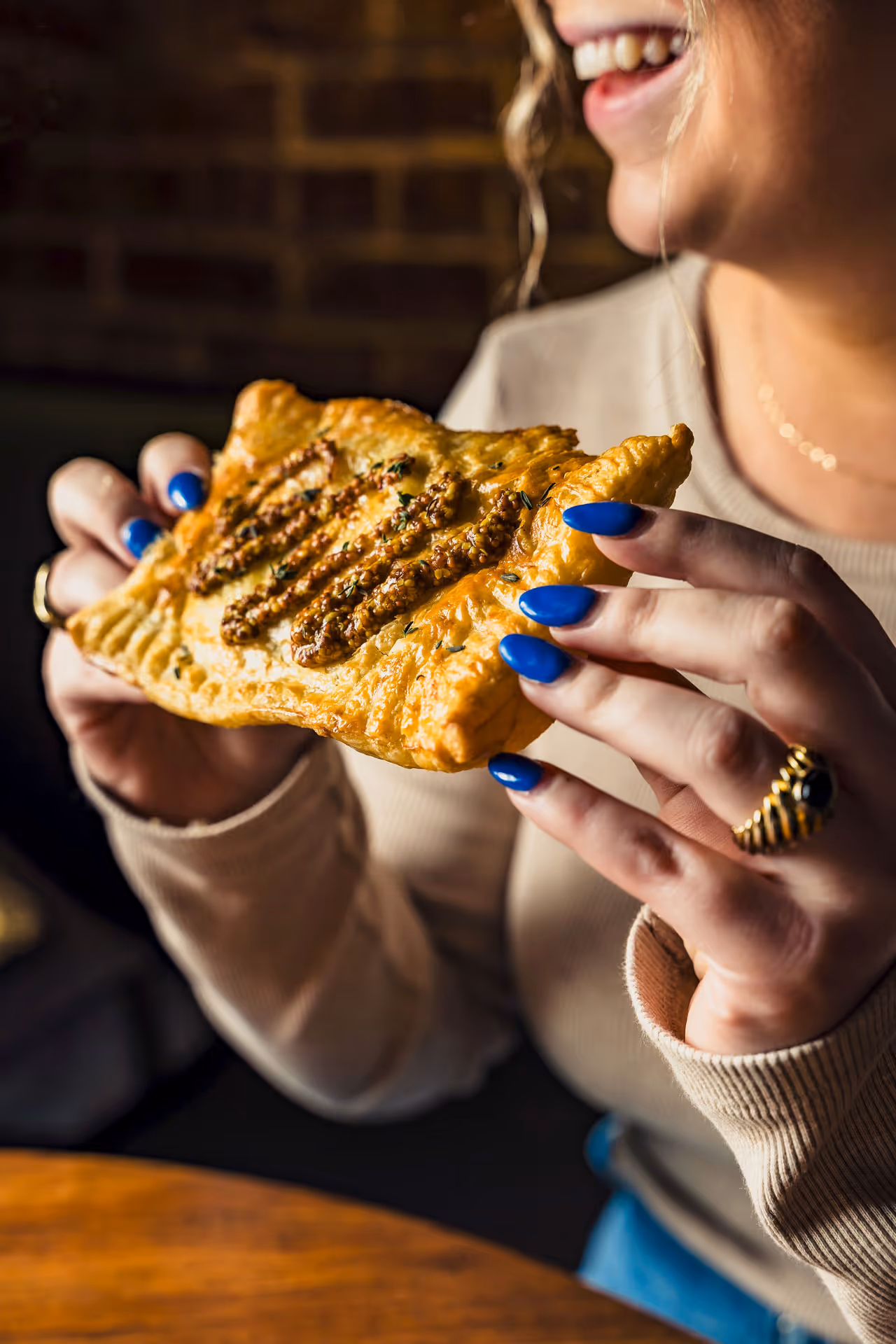 A woman is holding a pastry with blue nails.