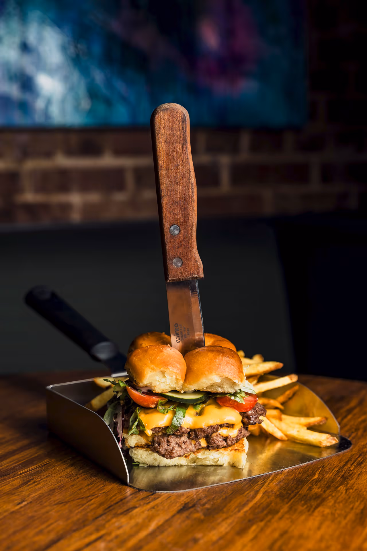 A large hamburger with lettuce, tomato, and cheese on a silver tray.