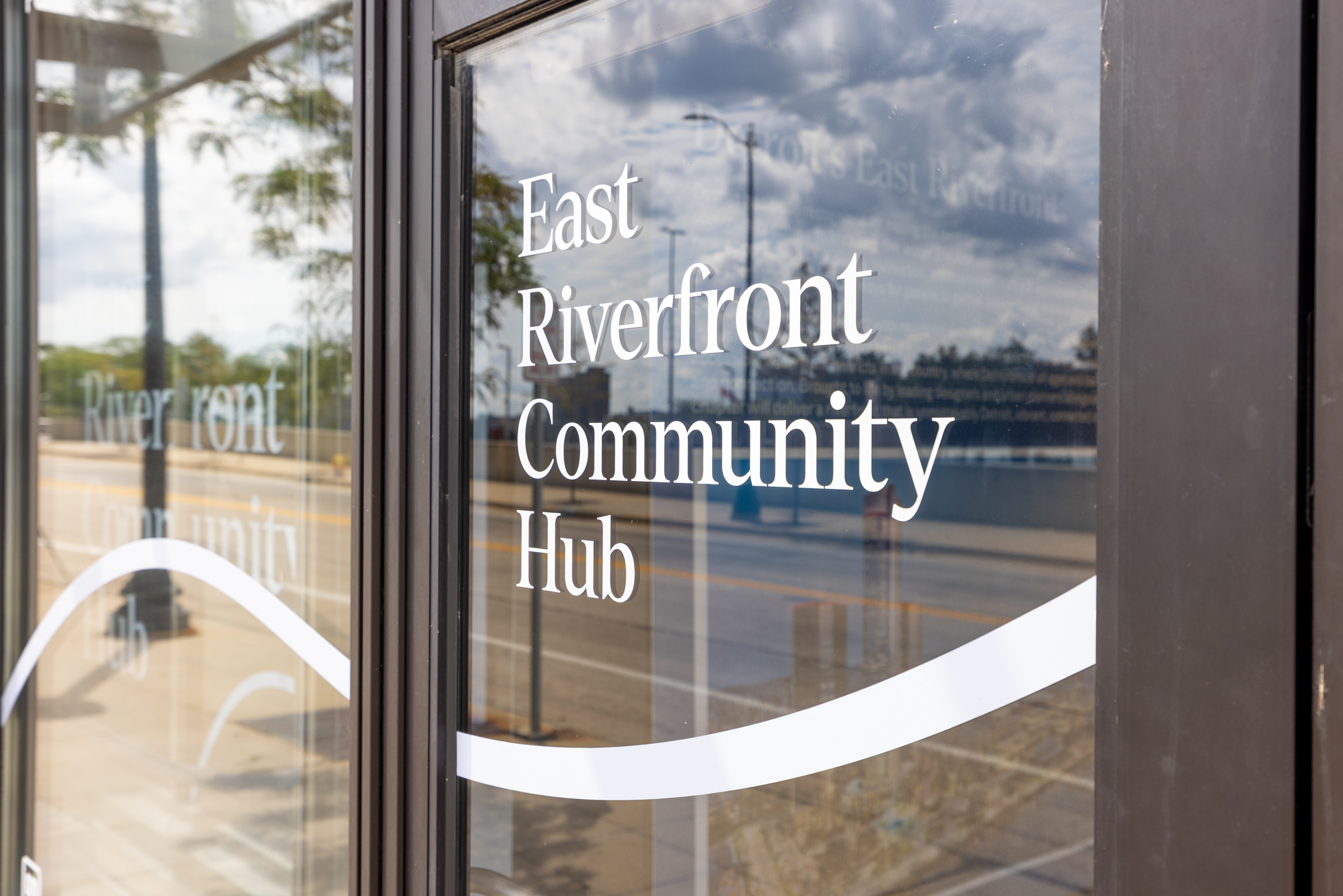 Exterior photo of the Community Hub at Beaubien Place in Detroit, Michigan, featuring window wrapping which says, "East Riverfront Community Hub."