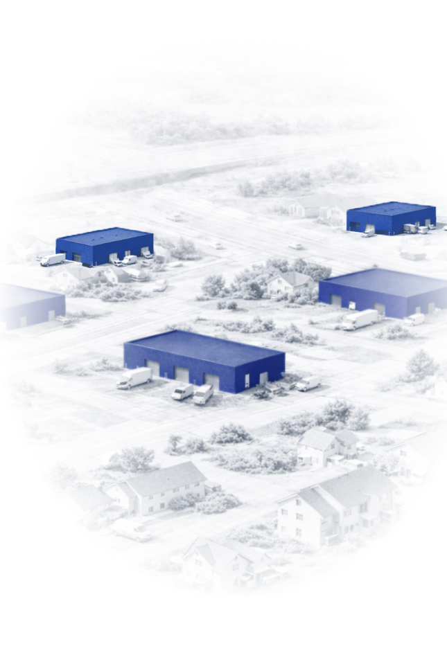 Aerial view of an industrial area with multiple blue warehouse buildings surrounded by roads and residential houses.