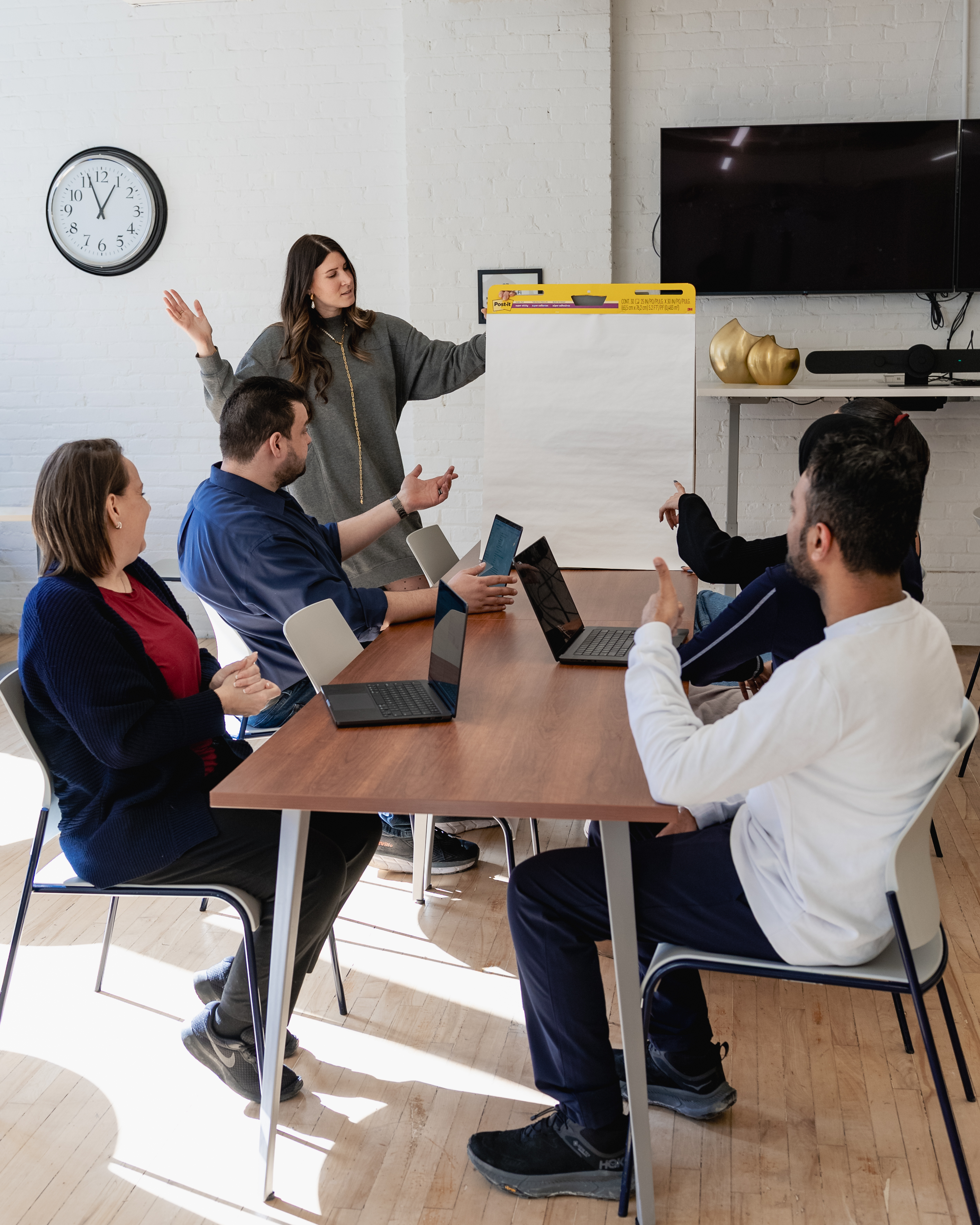 Two open gift boxes on a wooden table containing assortments of rectangular and square Indian sweets arranged in separate compartments.