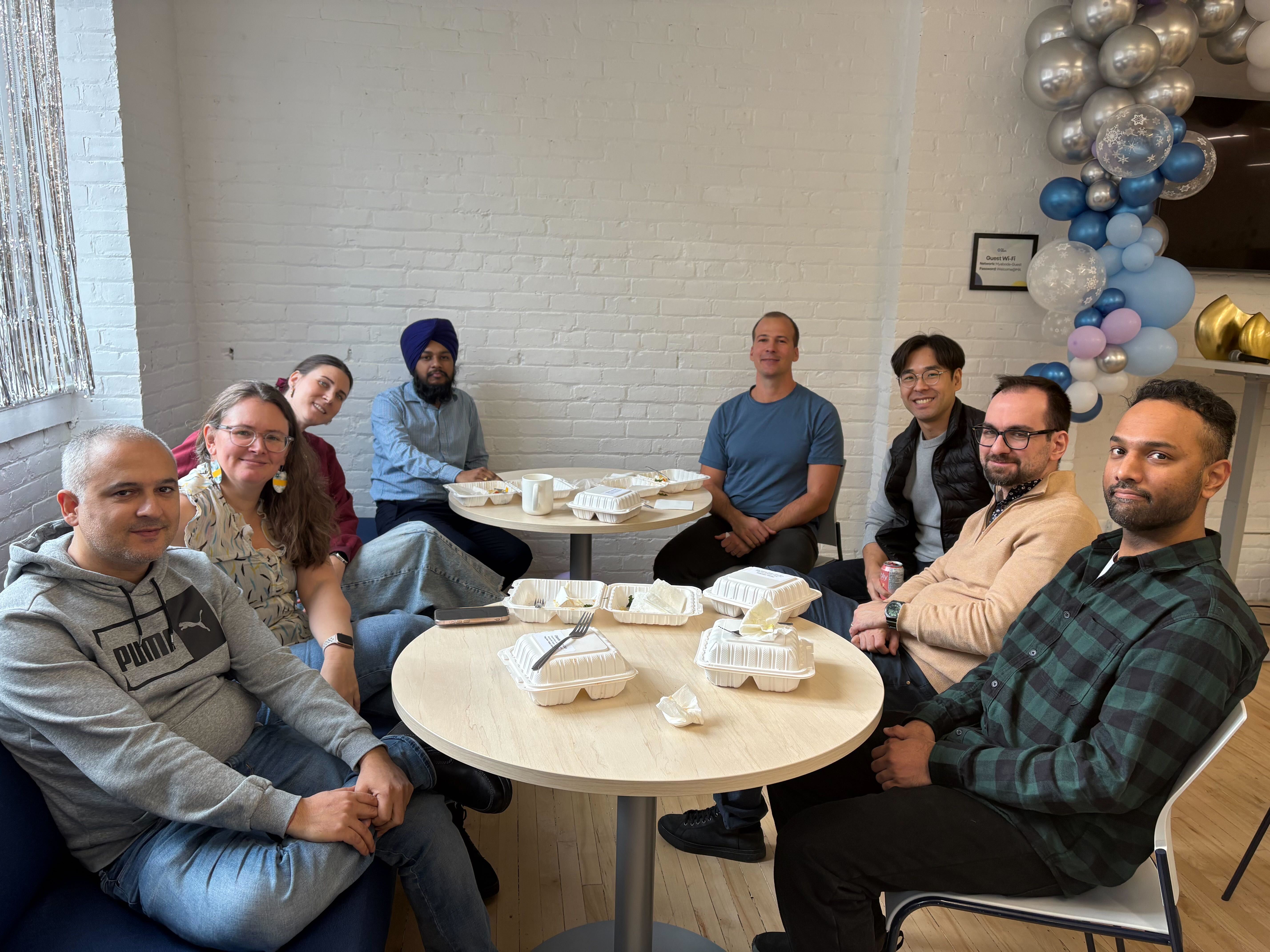 Three white plates on a wooden table with assorted pastries including croissants, donuts, and sandwich pieces.