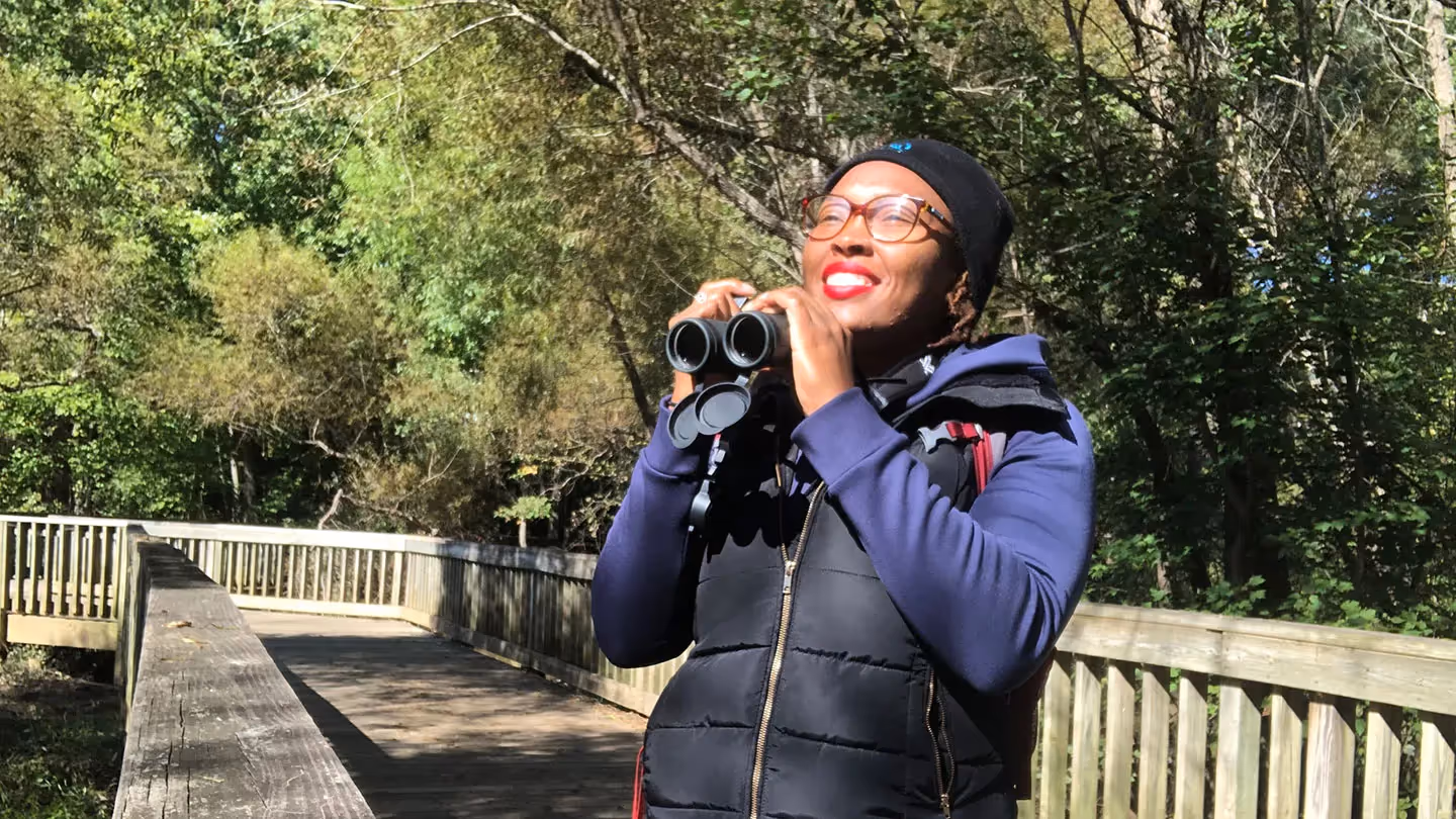 Deja Perkins standing in a park and holding a pair of binoculars