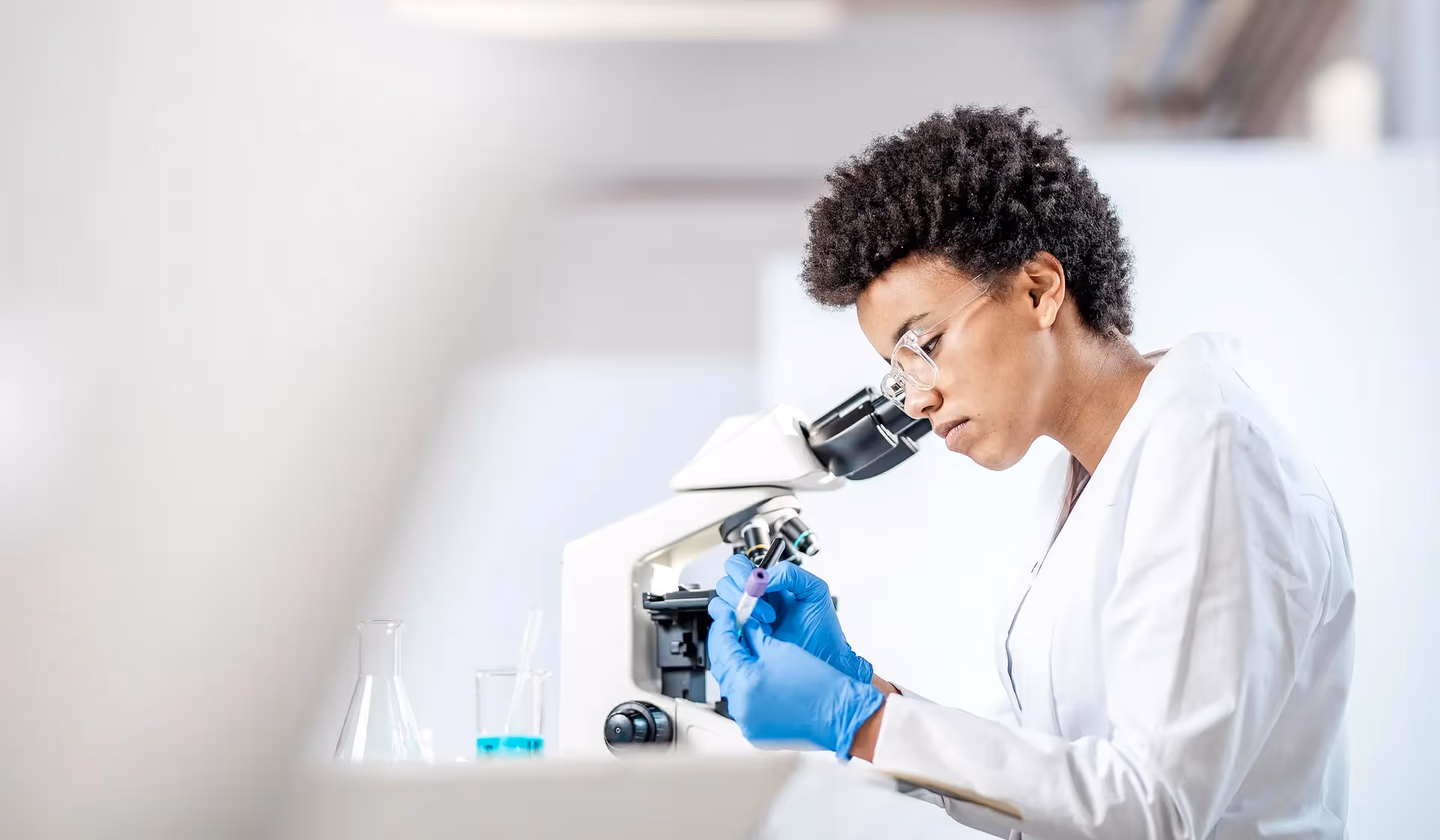 Young Black scientist looking into a microscope in a lab
