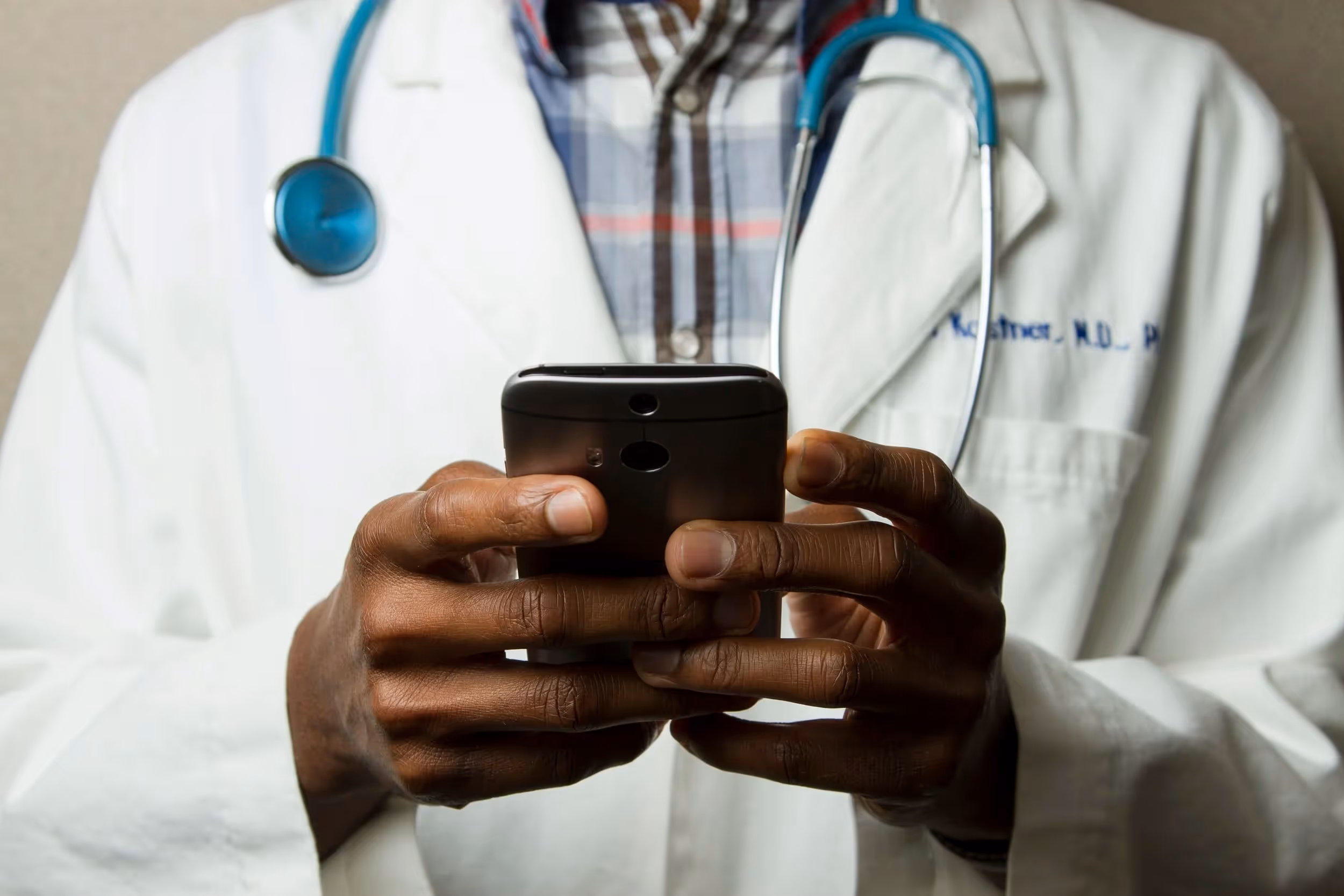 Black scientist in a lab coat holding a cell phone in his hands