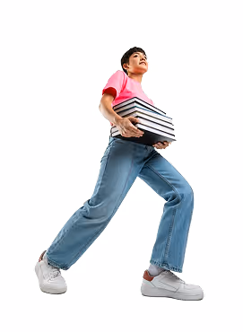 Young person in a pink shirt and jeans carrying a stack of books.