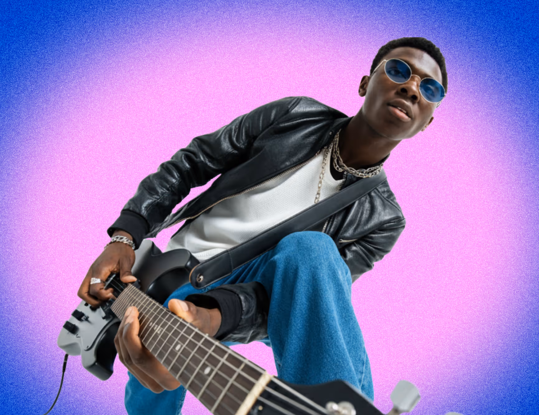 Young man wearing sunglasses and a leather jacket playing an electric guitar against a pink and blue gradient background.